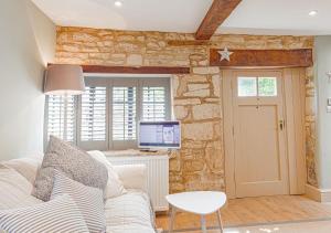 a living room with a white couch and a tv at Mill House Cottage - Star Stay on The Cotswold Way in Harescombe