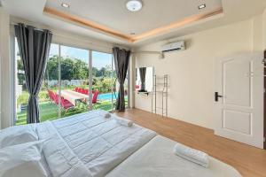 ein Schlafzimmer mit einem Bett und einem großen Fenster in der Unterkunft Anny poolvilla 5 bedroom ATV free in Ban Lum Phli + 22 Fotos