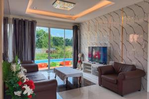 ein Wohnzimmer mit zwei Sofas und einem Fernseher in der Unterkunft Anny poolvilla 5 bedroom ATV free in Ban Lum Phli