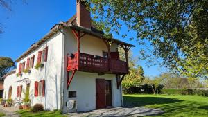 a white building with a balcony on the side of it at Maison d'hôtes MOURENIA Aroue in Aroue