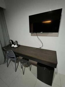 Un escritorio de madera con un televisor en la pared. en Cityscape Hotel - Studio Unit, en Mandaue