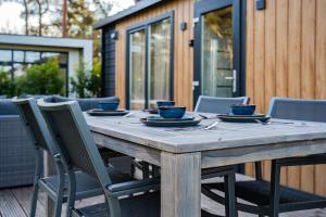 a wooden table with chairs and blue cups and plates at Wellnesshuisje in de Sallandse Heuvelrug in Haarle