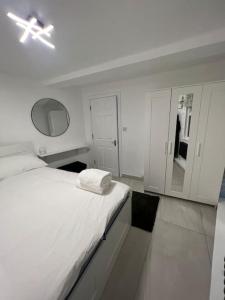 a white bedroom with a bed and a ceiling fan at Stunning 2 bed apartment located on high street, 5 minutes from New Cross station, free parking, 1 minute from famous 5 star Lit shisha bar and restaurant in London