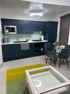 a kitchen with blue cabinets and a table and chairs at Stunning 2 bed apartment located on high street, 5 minutes from New Cross station, free parking, 1 minute from famous 5 star Lit shisha bar and restaurant in London