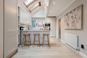 une cuisine avec deux tabourets de bar et un comptoir dans l'établissement High Tides Elegant & Modern 4-Bedroom Villa in Sandbanks, à Sandbanks