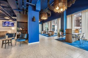 セリにあるHôtel AKENA Serris - Val d'Europeの青い壁のロビーには、椅子とテーブルが備わります。