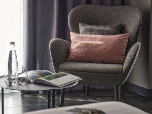 a chair with a pillow and a book on a table at Number 11 St Julian's Malta - Handwritten Collection in St. Julianʼs
