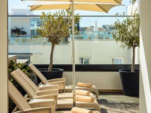a group of chairs and an umbrella on a balcony at Number 11 St Julian's Malta - Handwritten Collection in St. Julianʼs