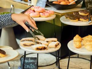 a woman is cutting pastries on plates in a bakery at Number 11 St Julian's Malta - Handwritten Collection in St. Julianʼs