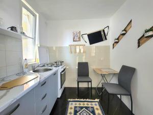 a small kitchen with a sink and two chairs at Geon Apartament in Prishtinë