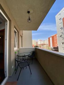 プリシュティナにあるGeon Apartamentの建物の上に椅子2脚とテーブルが置かれたバルコニー