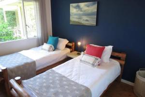 a room with two beds and a window at Whispering Woods Cottage in Natureʼs Valley