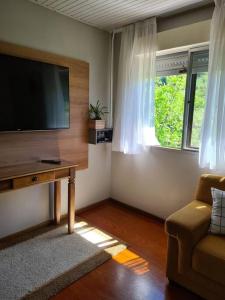 a living room with a flat screen tv and a couch at Refúgio Cantinho Verde in Pinto Bandeira
