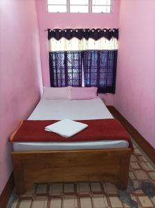 a small bed in a pink room with a window at Kirtti Inn Mini Home in Guwahati