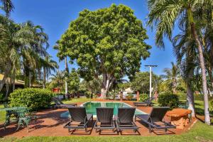 a wooden bench sitting in front of a palm tree at Bayside Holiday Apartments in Broome