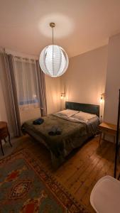a bedroom with a bed and a chandelier at Villa des roses, comme à la maison in Cherbourg en Cotentin