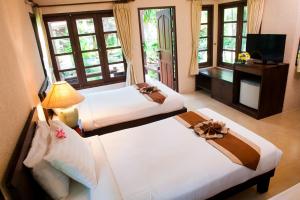 a hotel room with two beds and a television at Montien House - SHA Plus in Chaweng