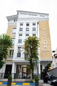 un edificio bianco con un cartello hotel sopra di Senator Hotel a Tirana