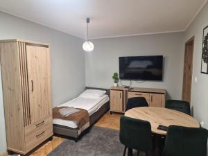 a bedroom with a bed and a table and a tv at Apartament Serce Wałcza in Wałcz