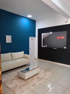 a living room with a couch and a large screen television at HOTEL JP in Delfinópolis