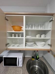 a kitchen with a counter with dishes and a microwave at Playa Jardín Bus terminal Pool in Puerto de la Cruz +18 photos