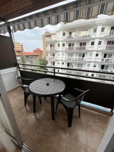 a balcony with a table and chairs and a large window at Playa Jardín Bus terminal Pool in Puerto de la Cruz