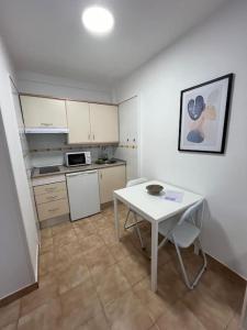 a small kitchen with a white table and a white table and chairs at Playa Jardín Bus terminal Pool in Puerto de la Cruz