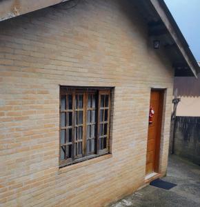 a brick house with a window and a door at Casa do Aconchego in Campos do Jordão