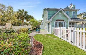 a green house with a white fence and a yard at Seaside Haven in Myrtle Beach