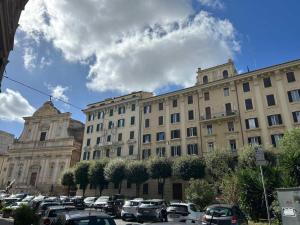 ein großes Gebäude mit auf einem Parkplatz abgestellten Autos in der Unterkunft I ricordi di San Pietro in Rom