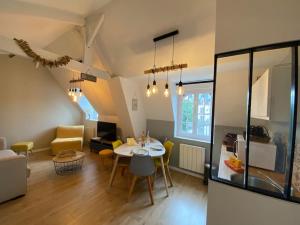 a dining room and living room with a table and chairs at Armonid au coeur de Cabourg in Cabourg +10 photos
