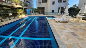 a swimming pool with two chairs and a table at Linda Vista do Mar - Espaçoso - Praia Pitangueiras in Guarujá