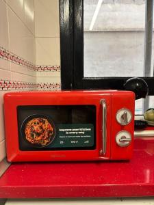 Un microondas rojo con un plato de pizza dentro. en Piso en el corazón de Alcañiz, en Alcañiz 6 fotos más