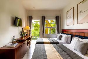 una camera d'albergo con due letti e una scrivania di Casanova Dalat Hotel a Da Lat