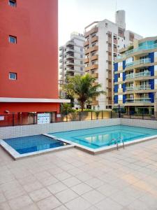 a swimming pool in front of some tall buildings at Um luxo de apartamento na Enseada in Guarujá