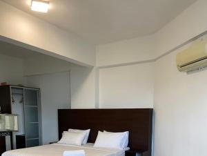 a bedroom with a bed with white sheets and white pillows at Marina Heights Apartment in Lumut +3 photos