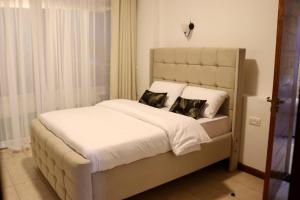 a bedroom with a bed with white sheets and pillows at Imagine Luxury Apartments in Nairobi