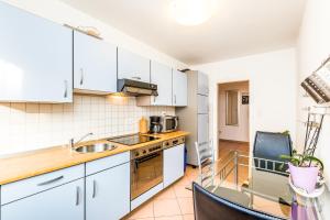 a kitchen with white cabinets and a glass table at Work & Stay Leverkusen in Leverkusen