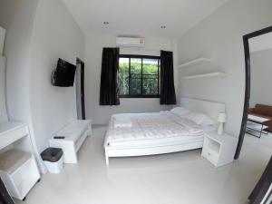 een witte slaapkamer met een bed en een raam bij Fairtex Residence Pattaya in Noord Pattaya