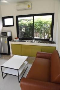 een woonkamer met een bank en een keuken met een raam bij Fairtex Residence Pattaya in Noord Pattaya