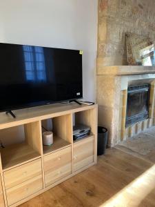 a large flat screen tv on a wooden entertainment center at Proche de SARLAT -Vue exceptionnelle in Carlux
