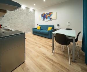a kitchen and living room with a table and a blue couch at Fix You Apartment Fco 2 in Fiumicino