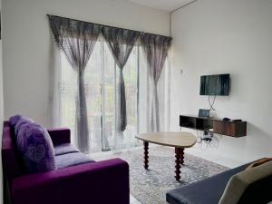 un salon avec un canapé violet et une table dans l'établissement Ammara Homestay Emerald Avenue Cameron Highlands, à Brinchang