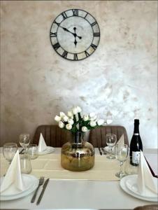 a table with a vase of flowers and a clock on the wall at Appartement à 10 min de Strasbourg in Strasbourg