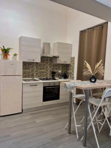 una cucina con elettrodomestici bianchi e un tavolo con sedie di Amira Guest House a Catania Altre 15 foto