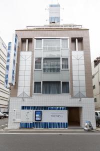 un edificio alto con un cartel delante en The Nell Ueno Okachimachi, en Tokio