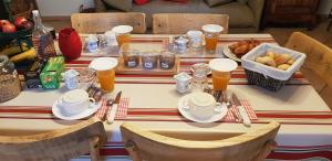 a table with a bowl of fruit and pitchers of orange juice at Maison d'hôtes MOURENIA Aroue in Aroue