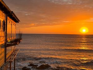 a sunset over the ocean next to a house at La Casa al mare Torre San Giovanni in Torre San Giovanni Ugento