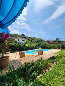 a swimming pool with chairs and a wooden deck at Pousada Recanto da Ladeira in Paraty