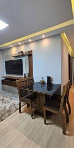 Un comedor con mesa y sillas y un televisor. en Apartamento Aconchegante, en Cuiabá